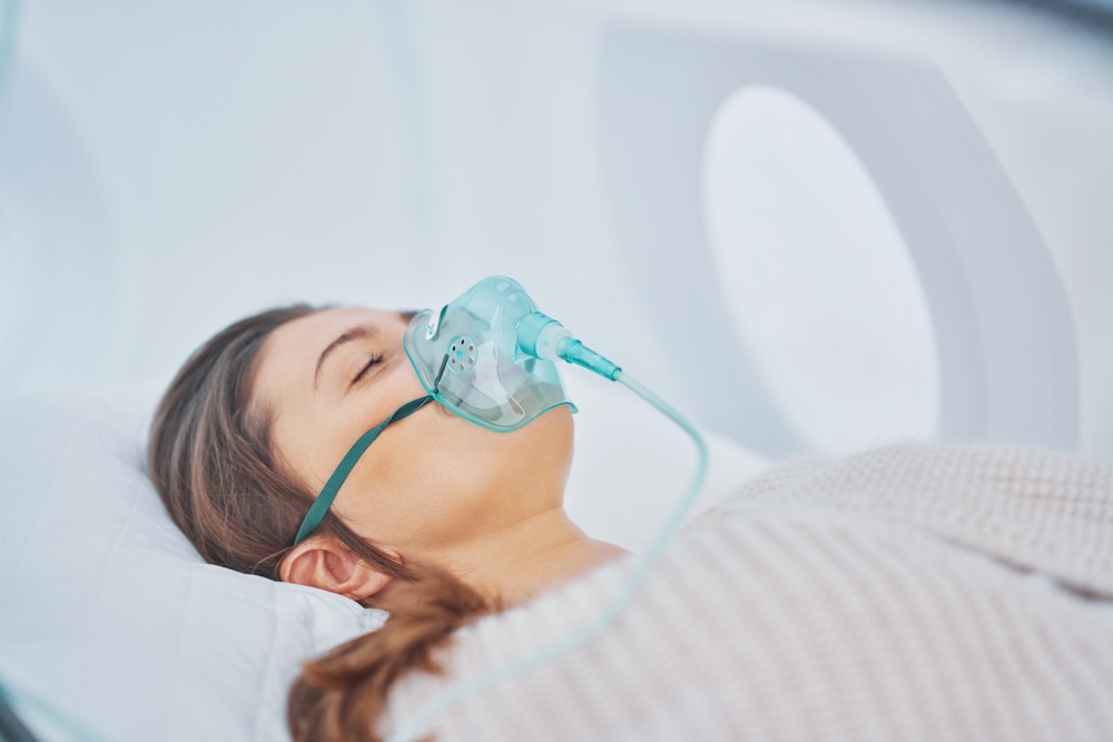 woman in hyperbaric oxygen chamber with blue oxygen mask