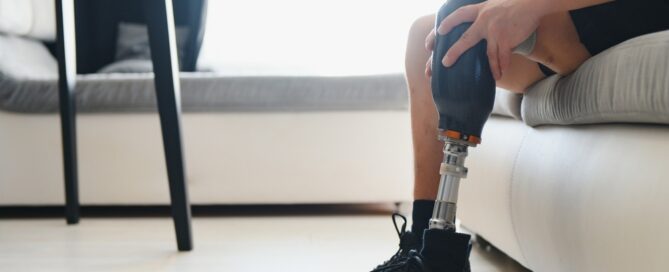 Someone sitting on a couch putting on a prosthetic leg.