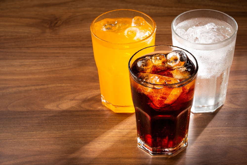 Three glasses of soda on a table.