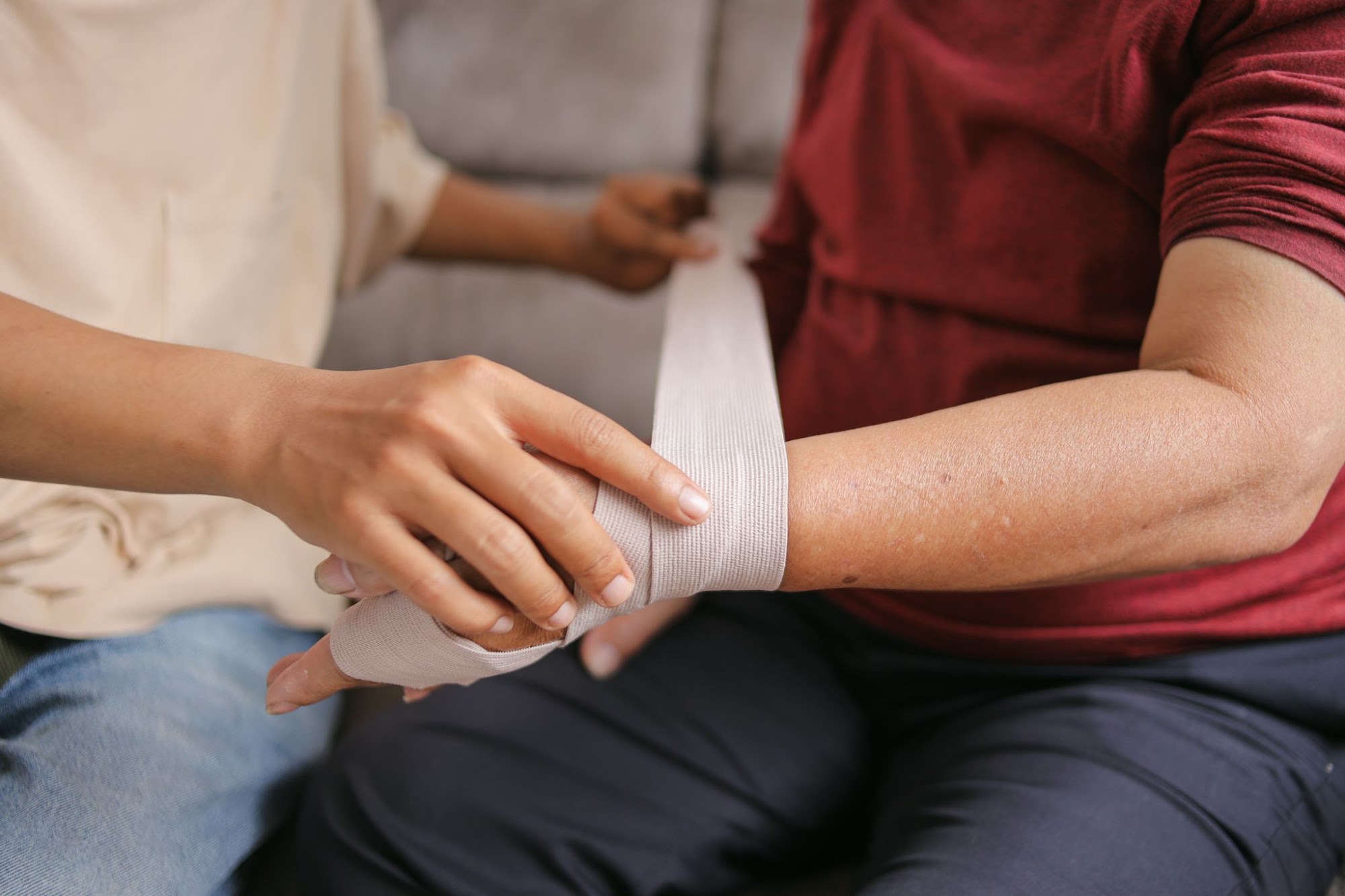 Caregiver bandaging a wound on a person’s wrist
