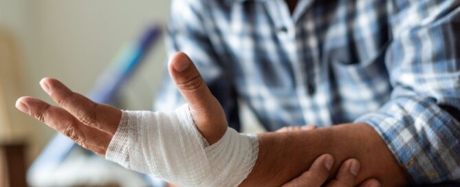 Older man holding his bandaged wrist and hand while recovering from a wound